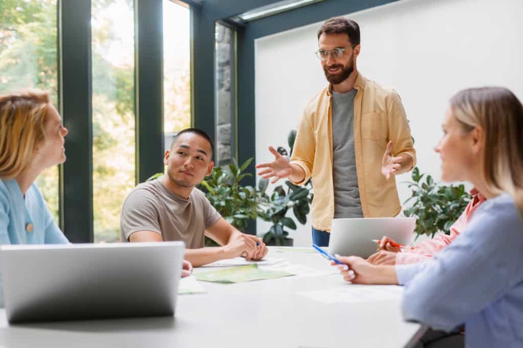 Man leading a discussion as colleagues listen attentively in a bright, relaxed meeting.