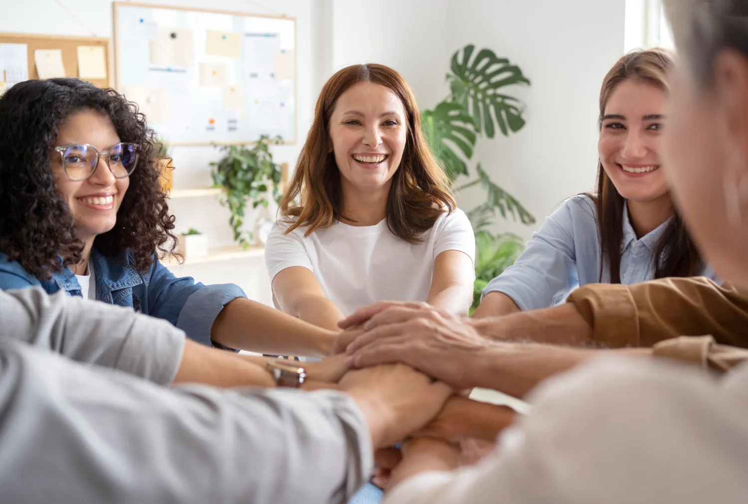A group of colleagues with their hands stackd in a huddle, smiling