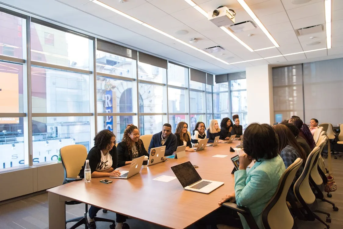 Large group of professionals gathered around a conference table during a corporate town hall
