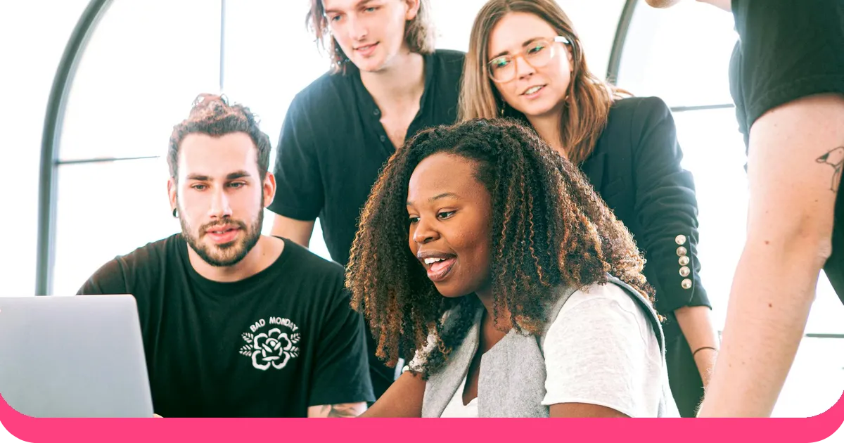 Diverse team collaborating on a creative presentation around a laptop with engaged expressions