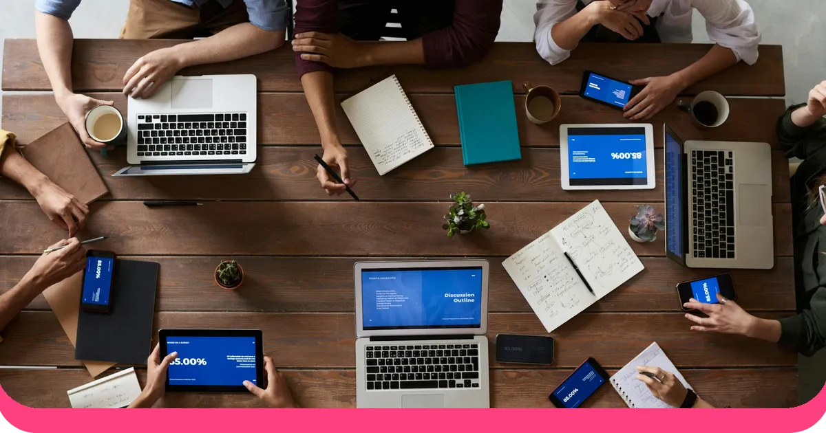 Overhead view of a team working on presentations with laptops tablets and slides showing data