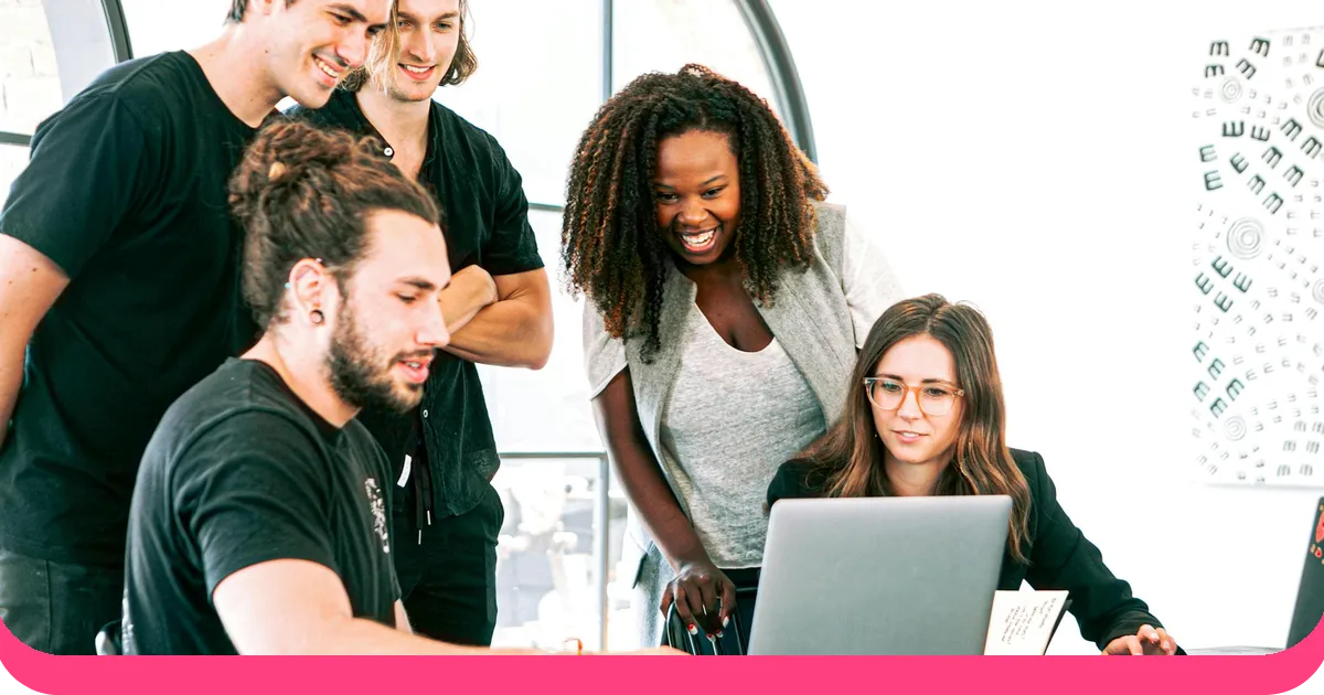 Diverse team collaborating on a presentation format around a laptop in a modern office