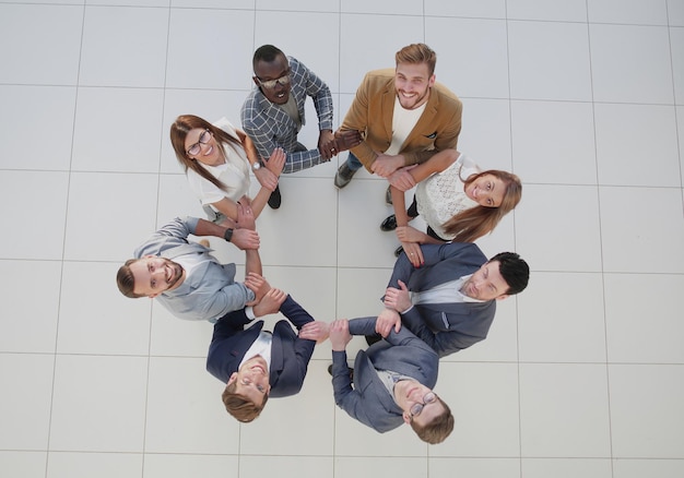 Diverse business team holding hands in circle viewed from above