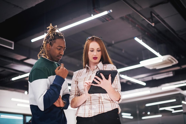 Two colleagues reviewing quiz answers on a tablet in a modern office