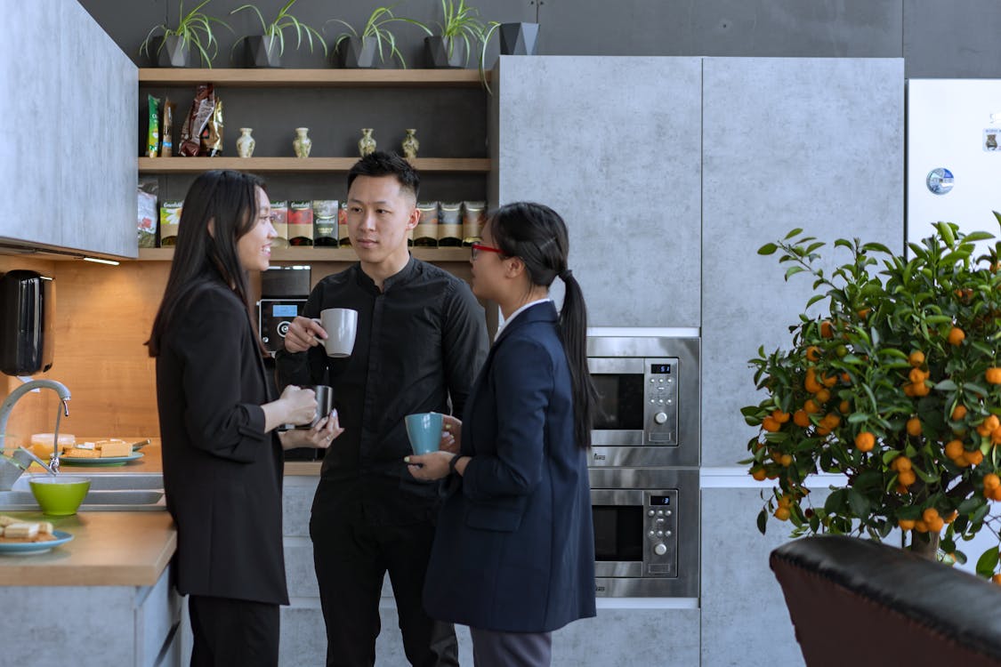 三位同事在辦公室廚房享受咖啡休息時間