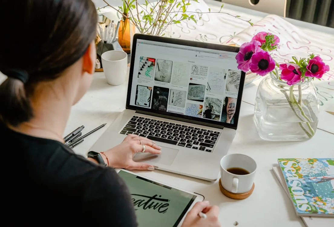 Person using a laptop for graphic design and content creation at a creative workspace