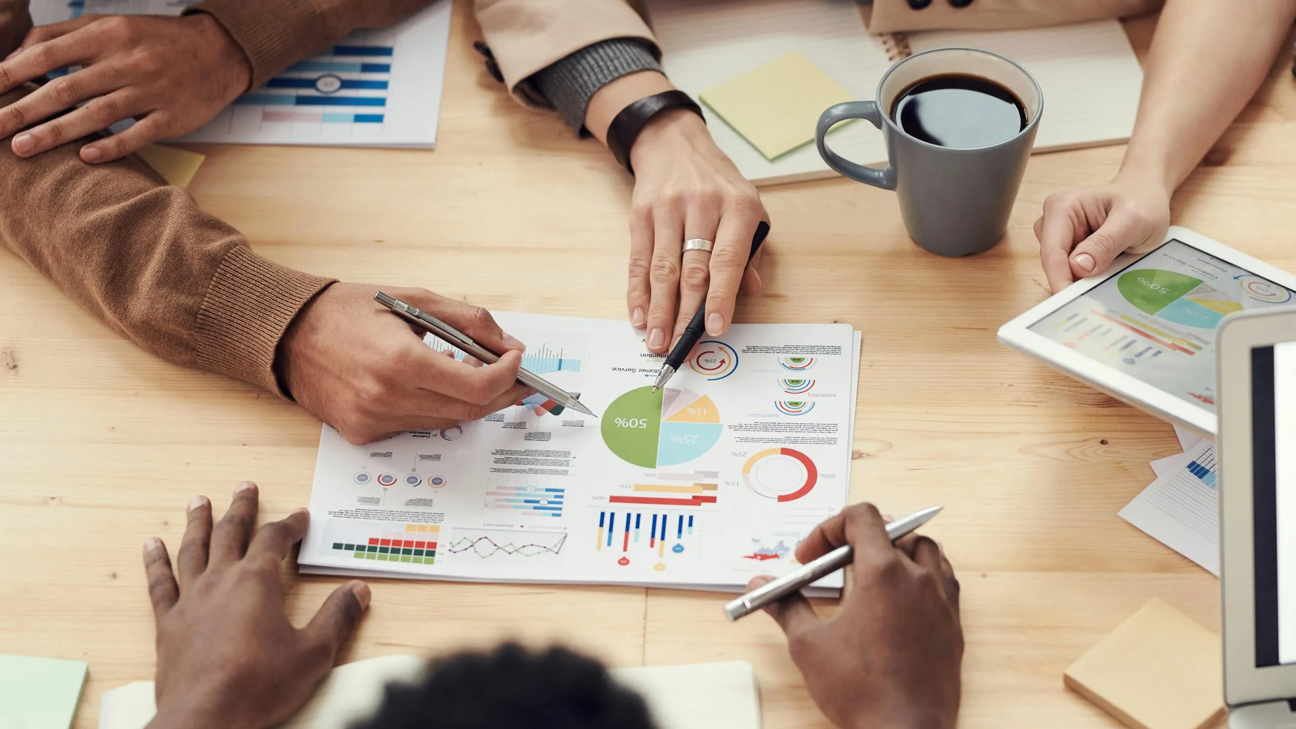 Team of professionals analyzing survey data charts and graphs around a conference table