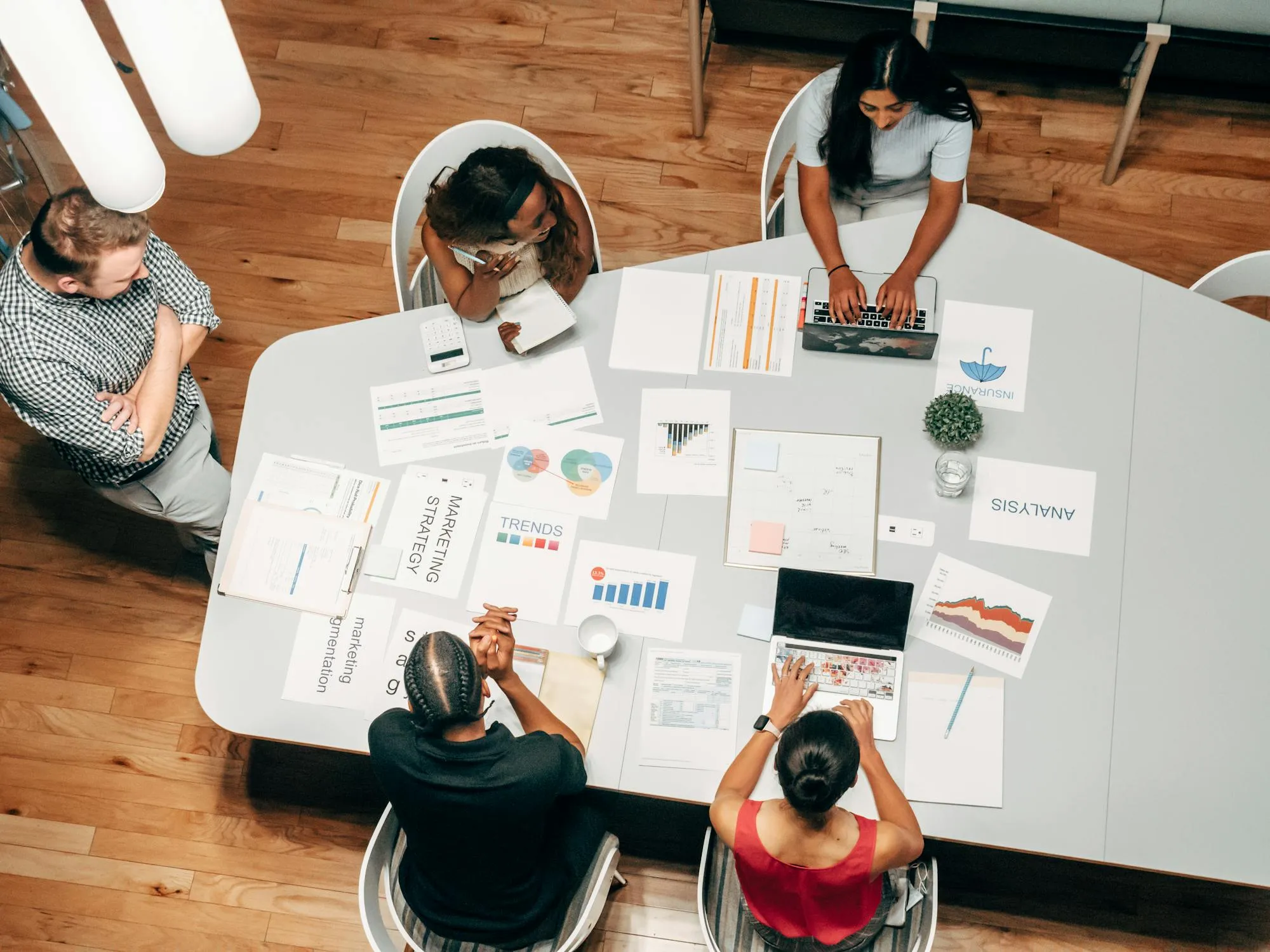 Overhead view of a marketing team reviewing survey analytics reports and trend data at a meeting