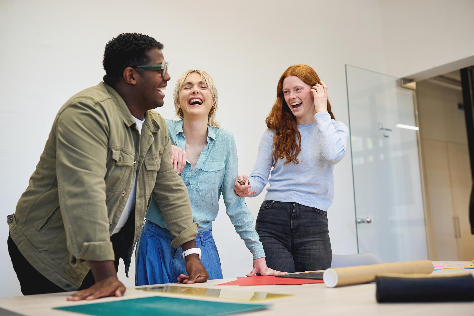 Colleagues collaborating and laughing together during a team activity in the office