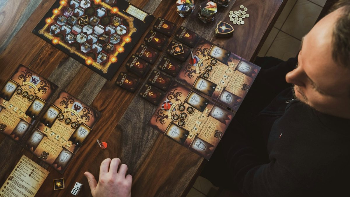俯視圖，一張桌子上擺滿了奇幻桌遊的棋盤和卡牌，玩家們正在公司聚會的桌遊角輪流玩遊戲。